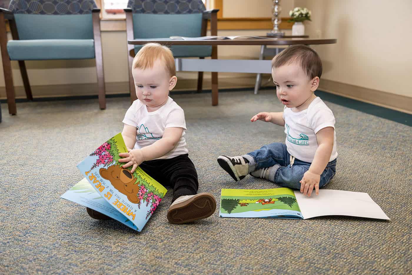 babies reading books on the floor
